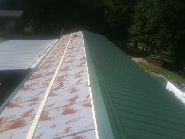 Old rusted panels beside newly installed green metal roofing — Wind Damage Roof Repair by Roofing Brothers in Sylmar