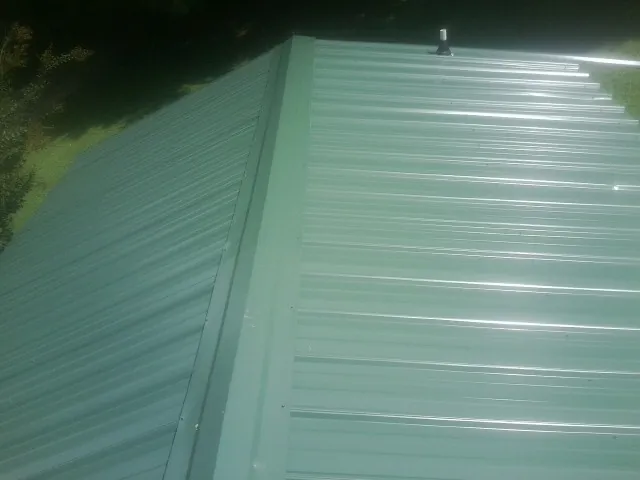 New green metal panels meeting at the ridge of a roof — Flat Roof Repair work by our crew in Sylmar