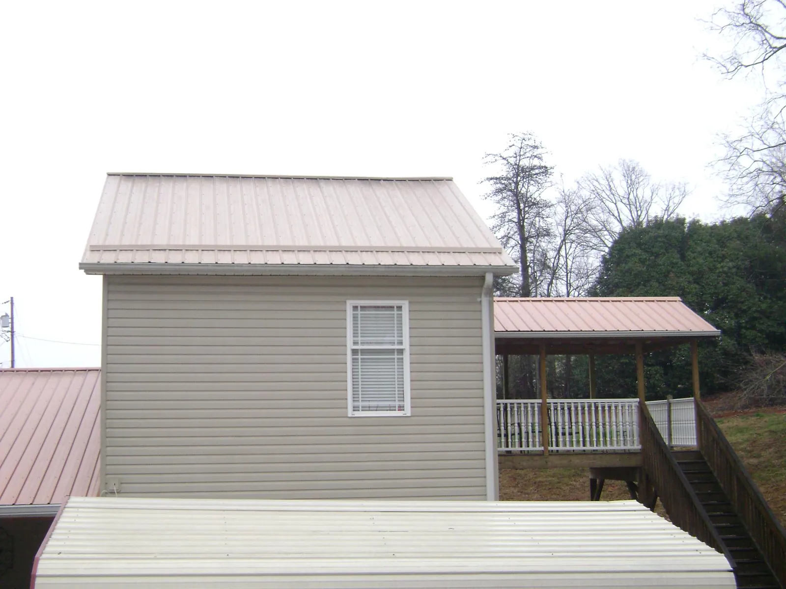 Tan metal roofs on a two story addition and attached porch, from a Roof Replacement job in Sylmar